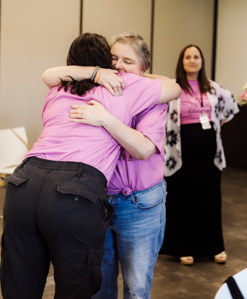 A woman mentor giving another woman a hug of encouragement